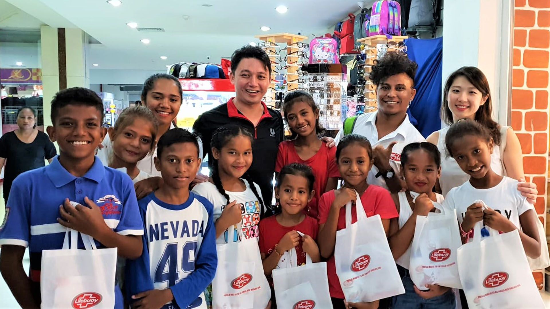 Group of young children holding Lifebuoy bags at an event to launch the brand in East Timor.