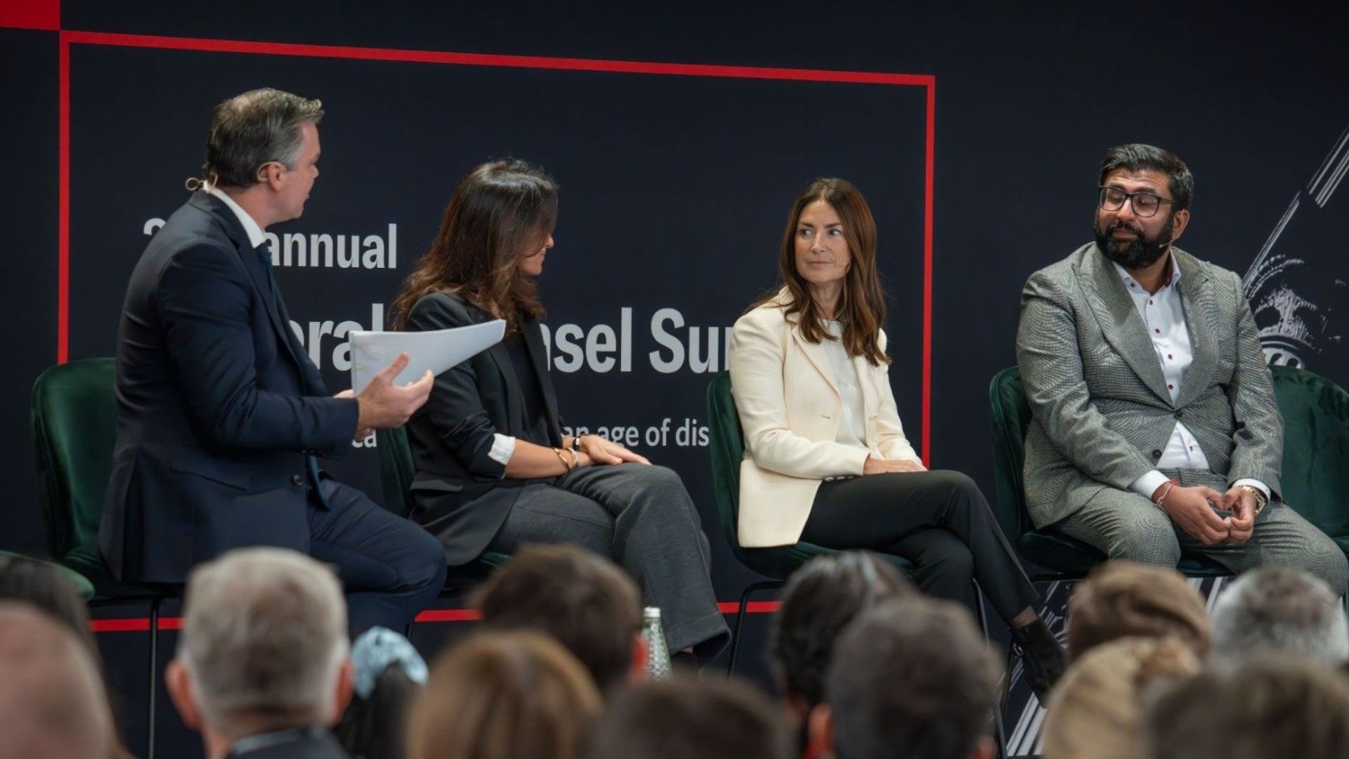Maria Varsellona sitting on a stage as part of a discussion panel with two men and one other woman