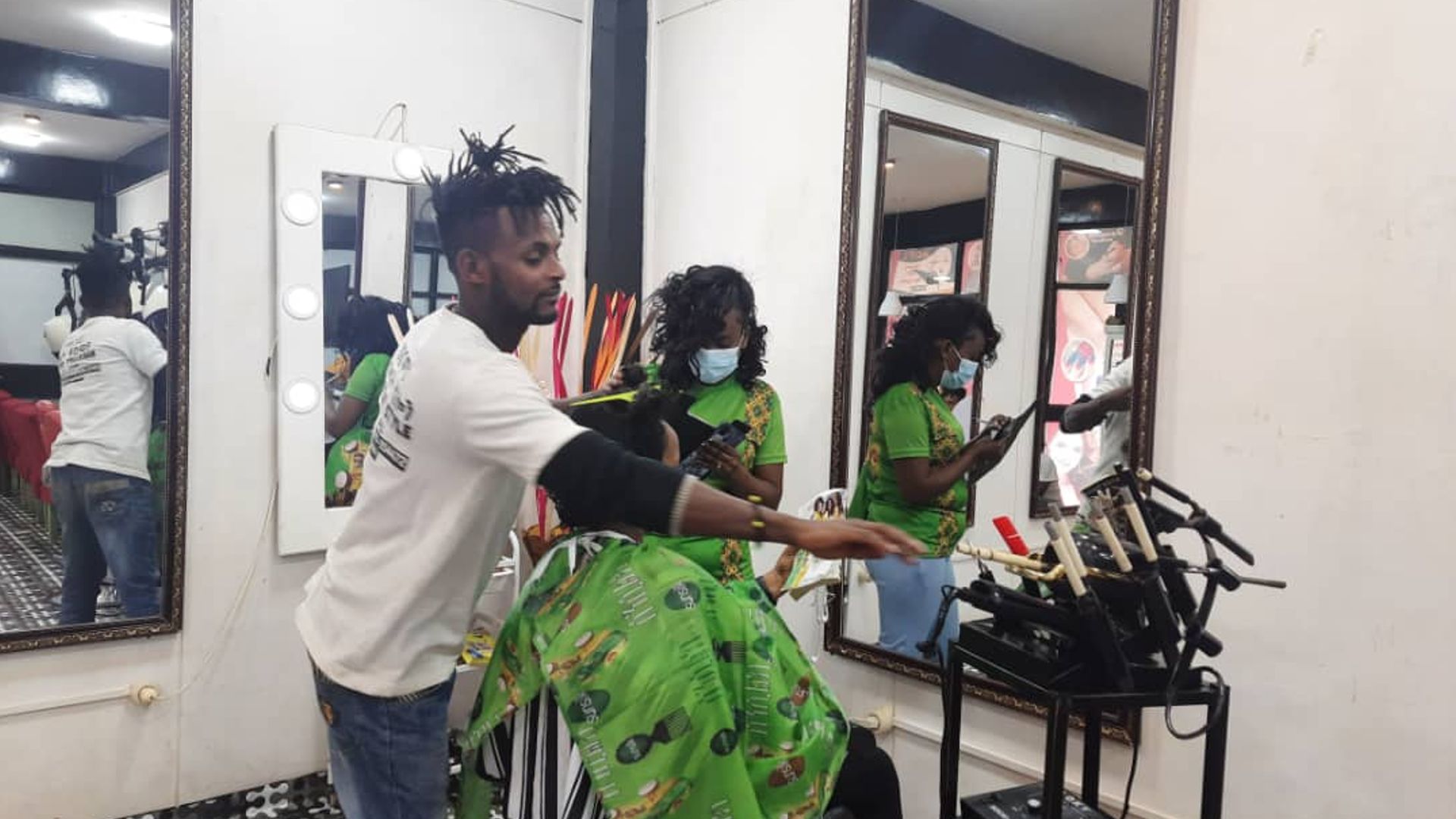 Man in hair salon styling and adding treatments to a woman’s hair