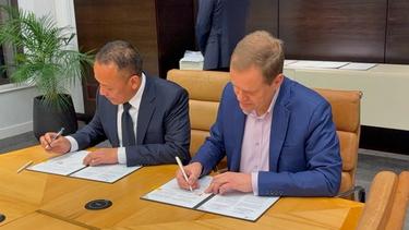 A photograph of Unilever's Chief Supply Chain and Operations Officer signing a long-term partnership with PT. Perkebunan Nusantara to source sustainable palm oil.