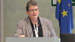 Julia Fentem speaking at a rostrum with EU flag to the right
