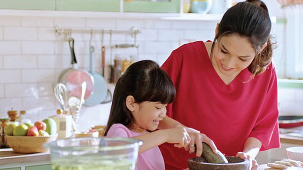A mother and daughter cook together in a kitchen