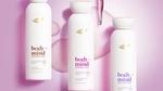 Three Dove Body+Mind serum body wash bottles displayed on a pink background with liquid droplets.