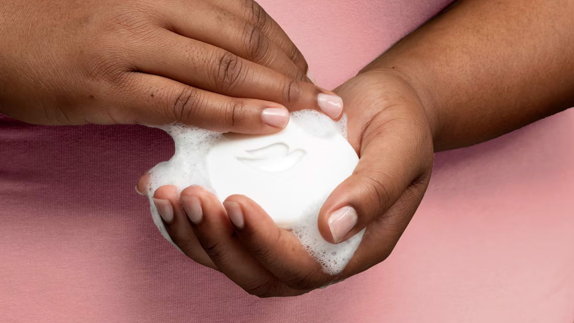 Close-up of a woman’s hands holding a lathering Dove Beauty Bar.
