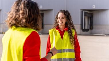 Two women dressed in high-visibility clothing having a conversation
