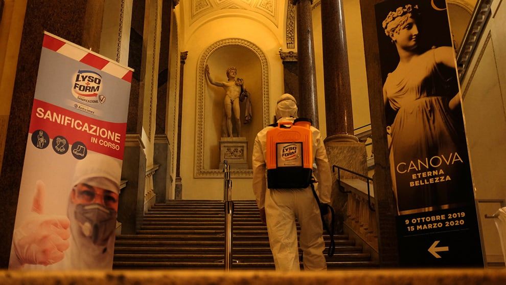 Cleaner wearing protective clothing and carrying a Lysoform spray backpack walking up steps in one of Italy’s main museums.