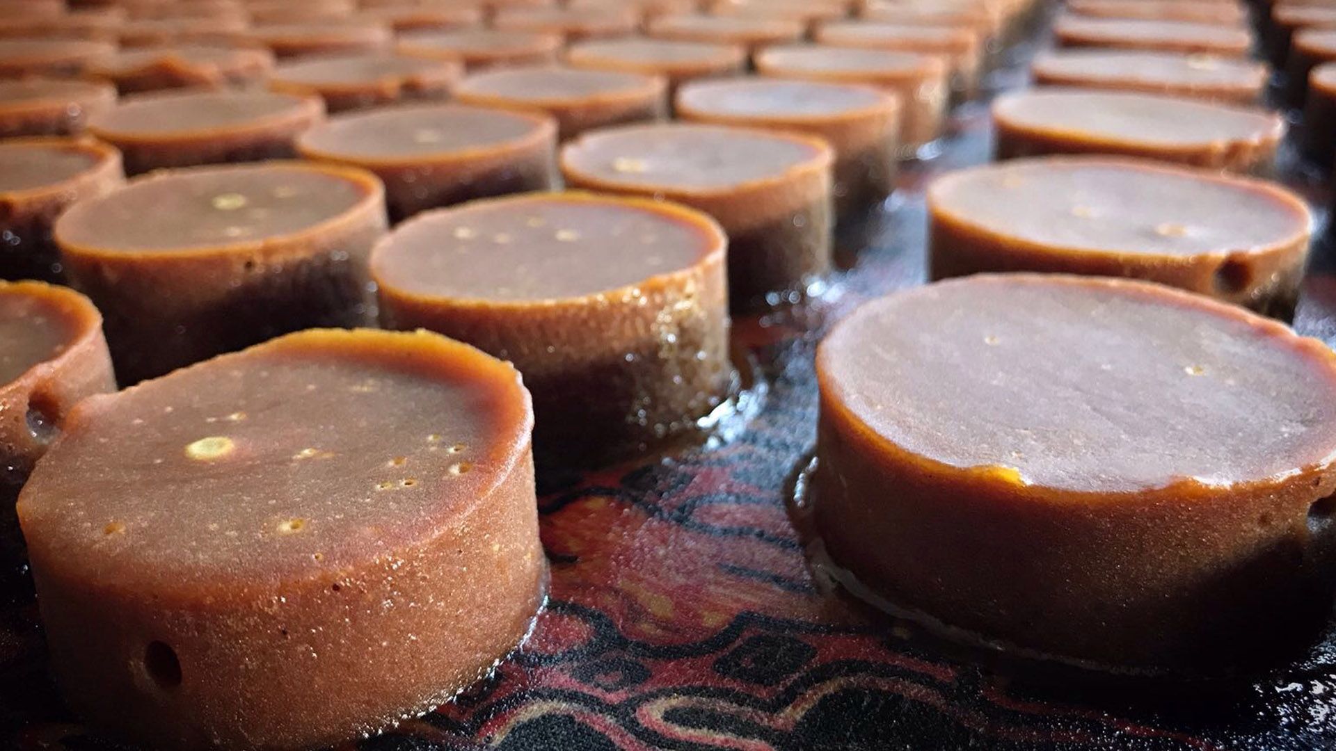 Round blocks of coconut sugar laid out on a table with a patterned covering.