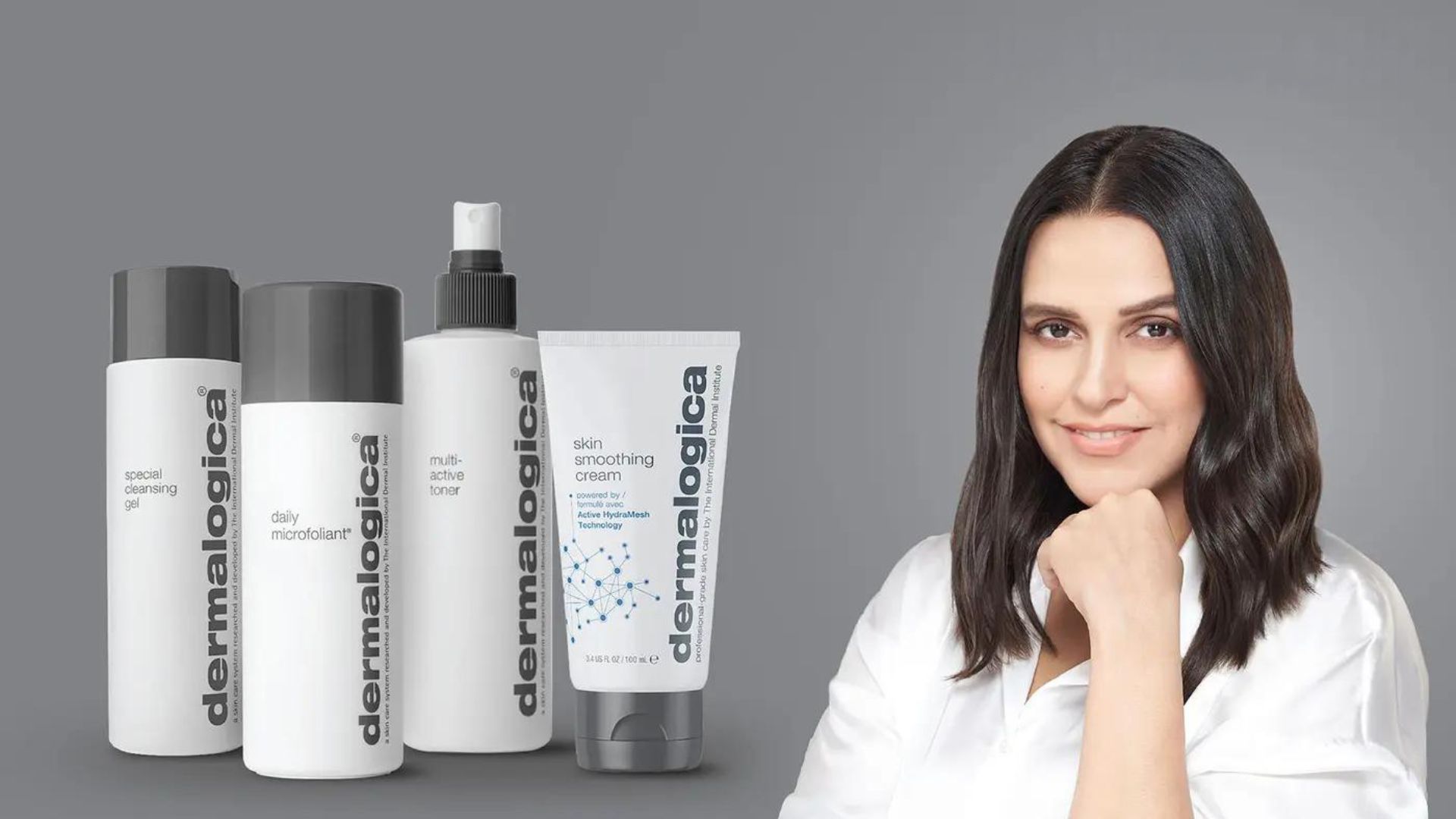 Woman smiling with her hand on her chin next to bottles of Dermalogica.