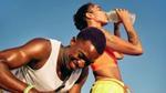 Man smiles as the woman beside him drinks from a bottle of Liquid I.V. and water during a pause in their outdoor activity.