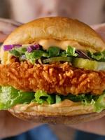 Person holding a crispy chicken sandwich with lettuce and pickles.