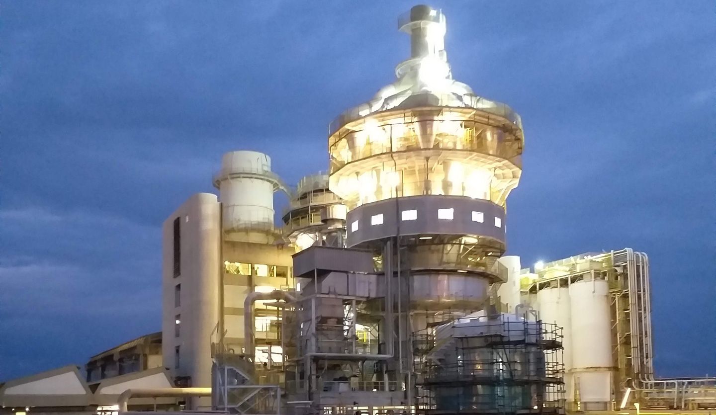 An illuminated factory tower against a dark blue night sky