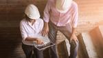 Two people in hard hats looking at a laptop