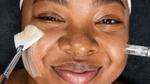 Young woman with melanin-rich skin undergoing a beauty treatment from a Dermalogica skincare professional