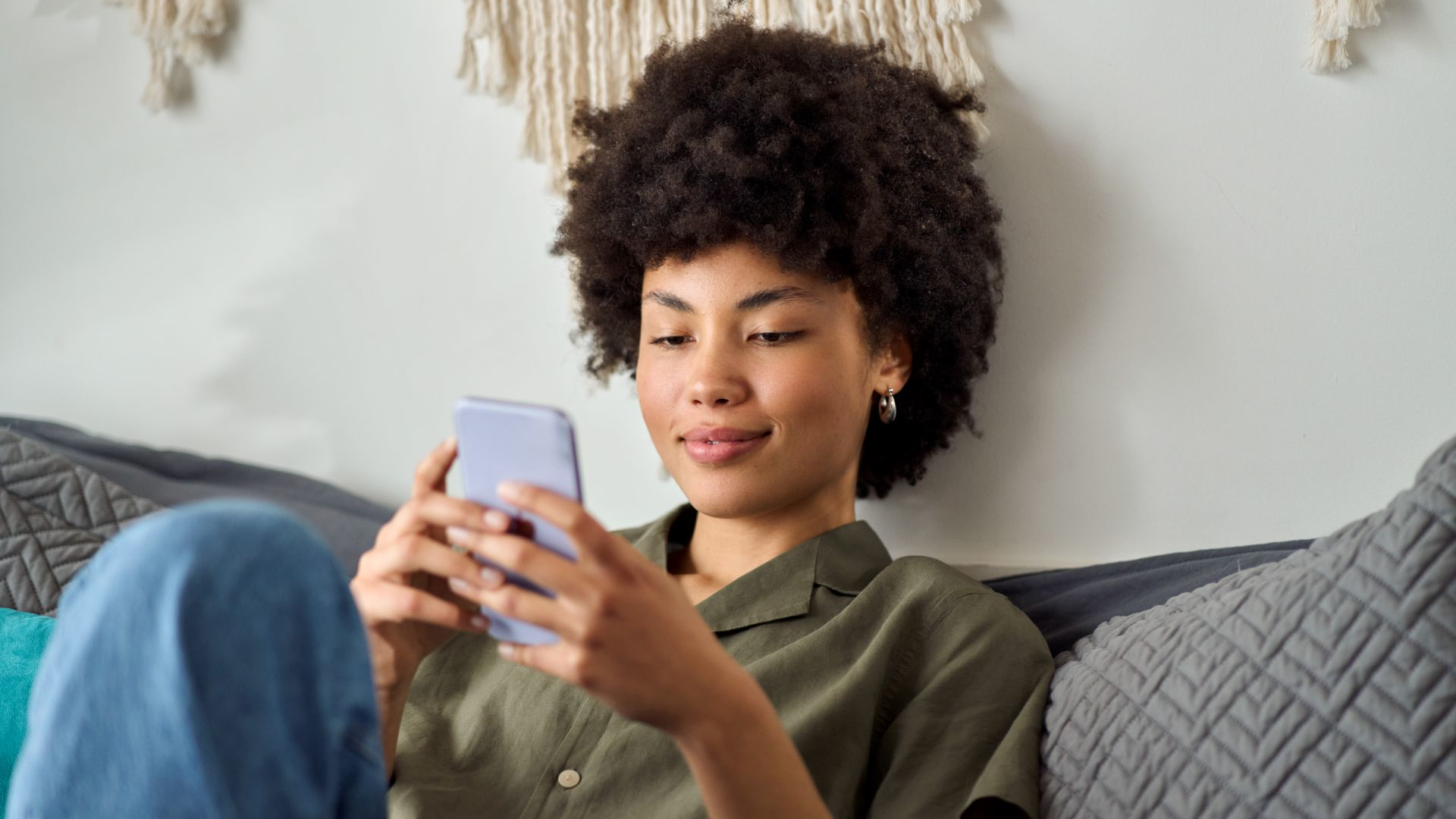 Young African American woman using smartphone at home.
