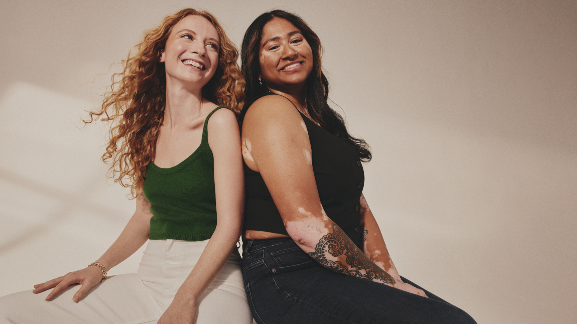 A pic from a Dove ad campaign. Two women sit back to back. One is white with long red hair, one has vitiligo and long dark hair.