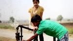 Two boys drinking and splashing water from a community water tap