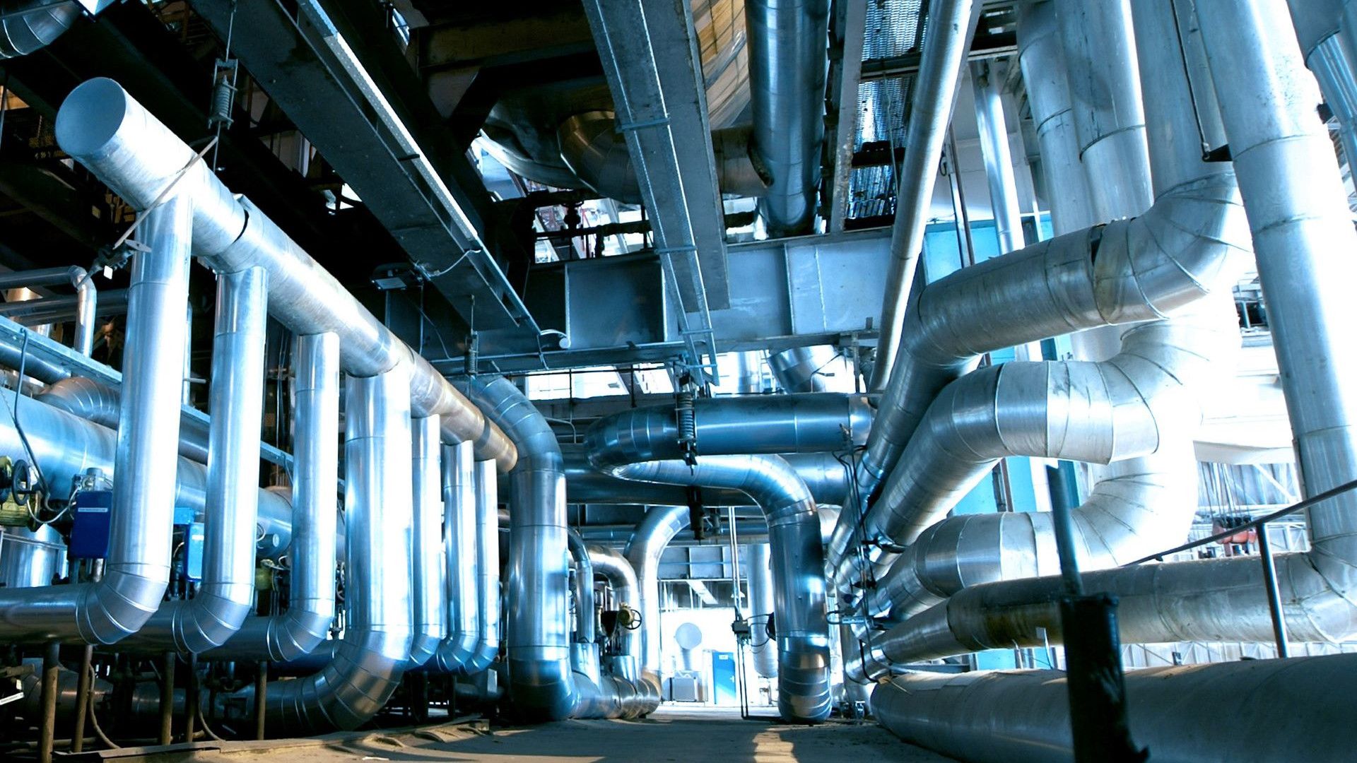 A modern industrial facility with large, interconnected metal pipes and ducts. 