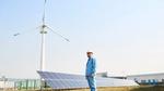 Worker in front of solar panels and wind turbine