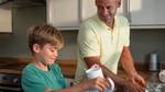 Father and young son in a kitchen doing the washing up together