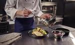 Chef in a commercial kitchen preparing a dish using a Knorr product.