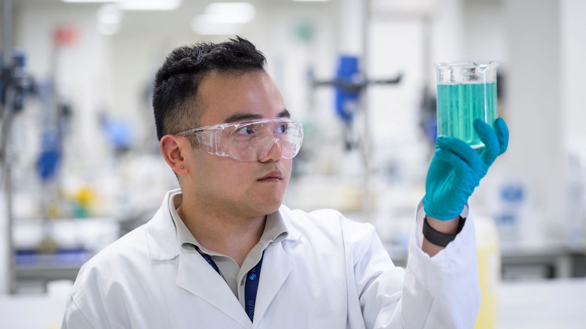 Image of a Unilever scientist in a lab looking at a glass of blue liquid.