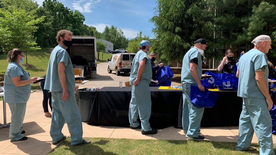 Medics at Mercy Hospital queuing up to receive Unilever gift bags, some holding prepacked meals