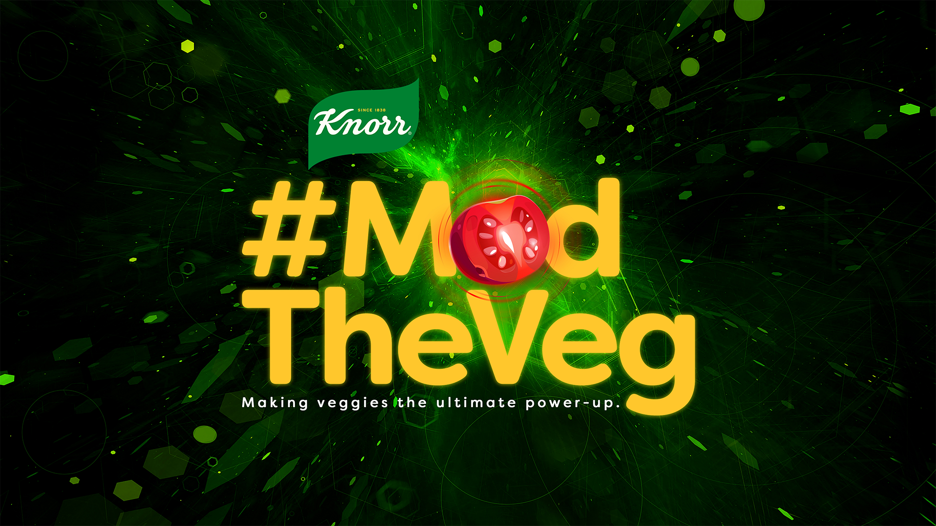 A green background with yellow text which reads: ‘#ModTheVeg’. The ‘o’ is represented by a sliced red tomato.