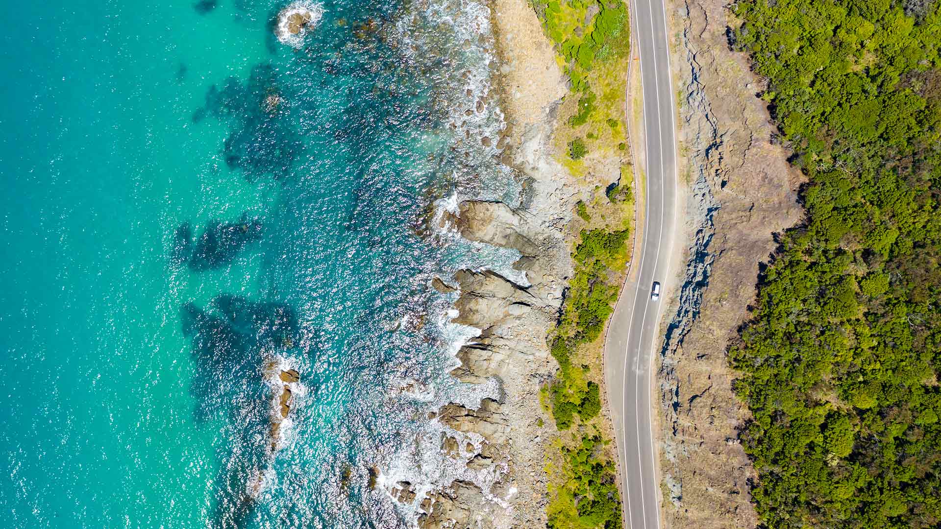 A car travelling along a road by the sea