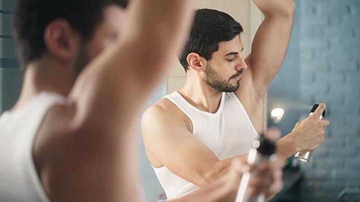 Man spraying deodorant onto underarm