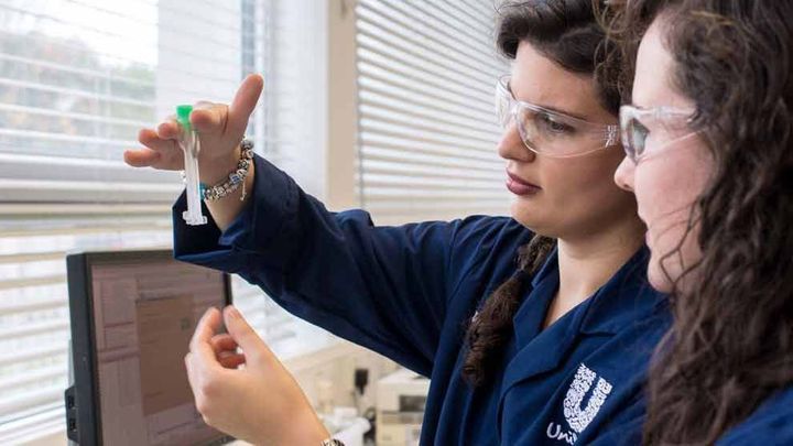 Two female Unilever scientists looking at a vial
