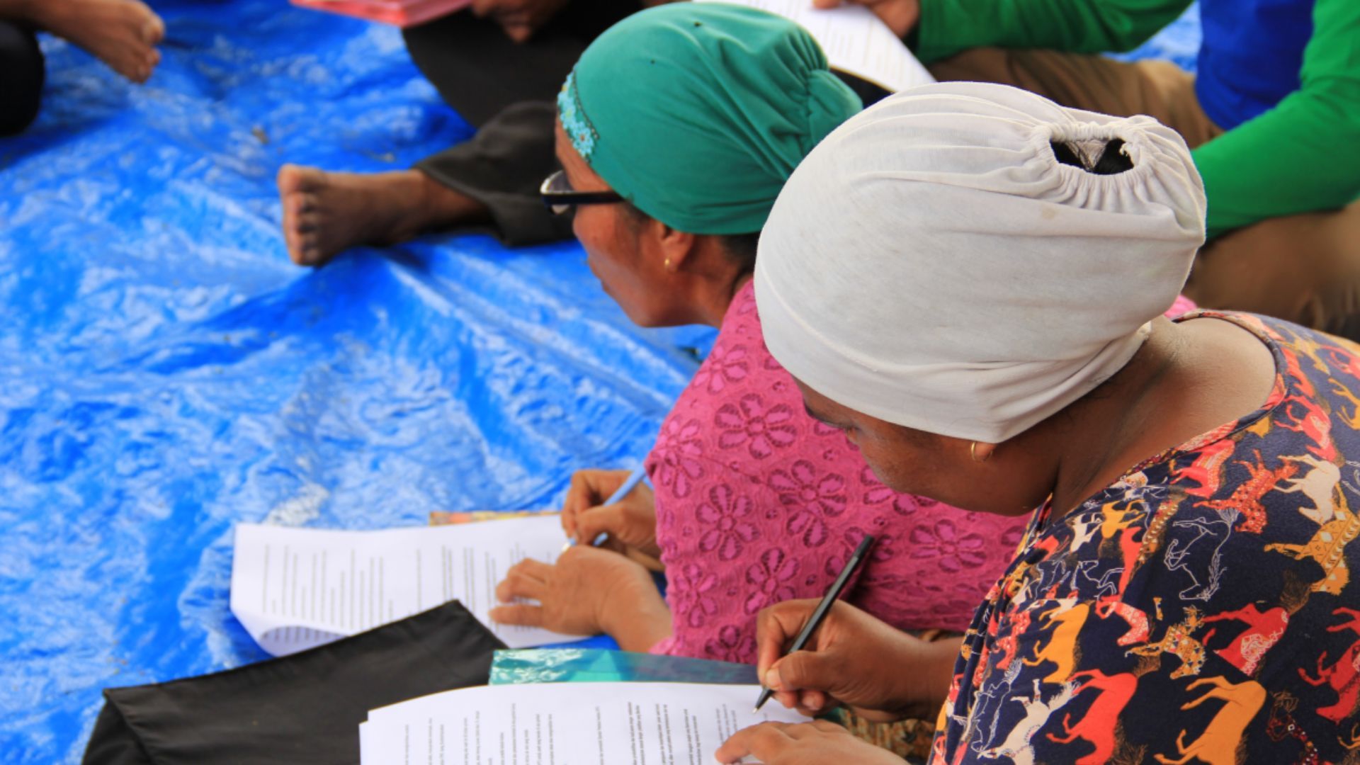 A group of women sitting on a floor writing notes