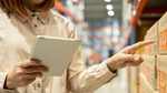 A person’s hand tapping their mobile phone screen to open an app and place a retail goods order