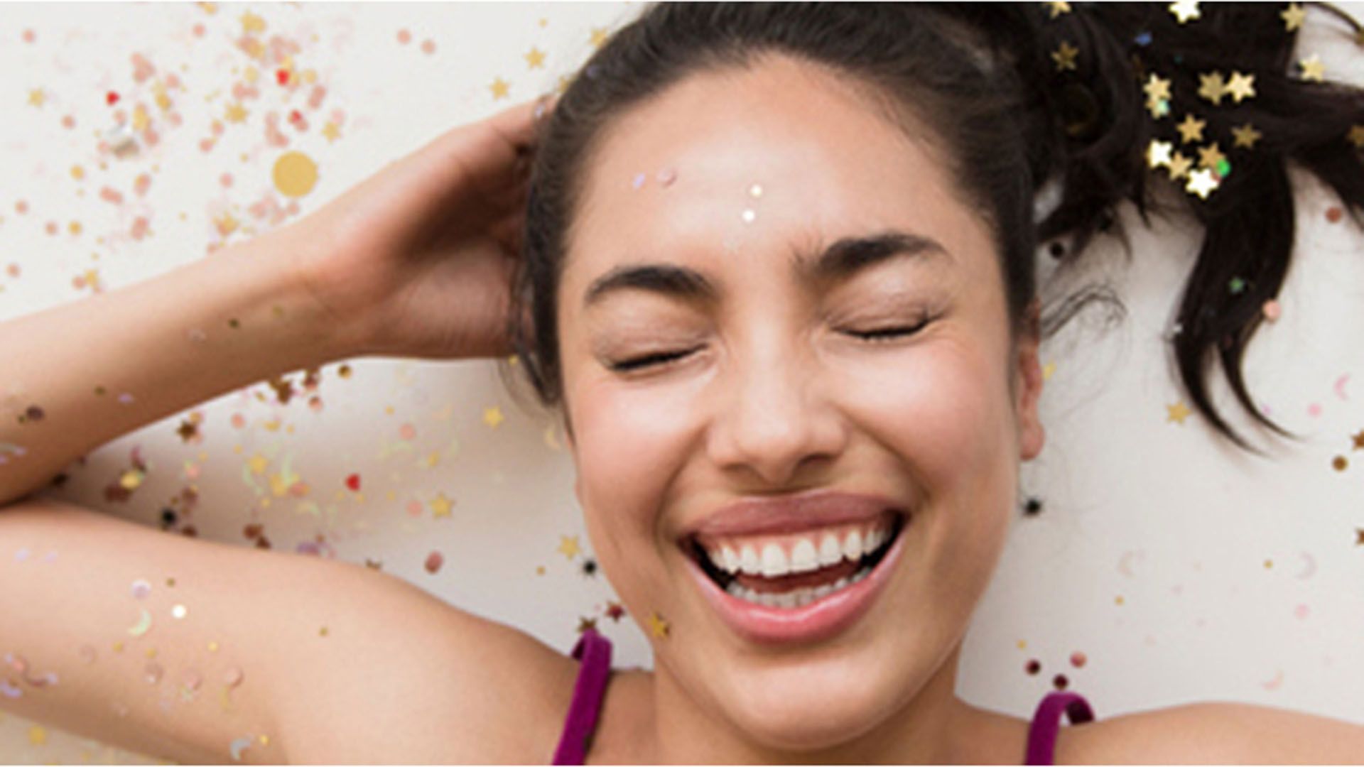Woman lying with her eyes closed with her hair loosely covered with glittery dandruff