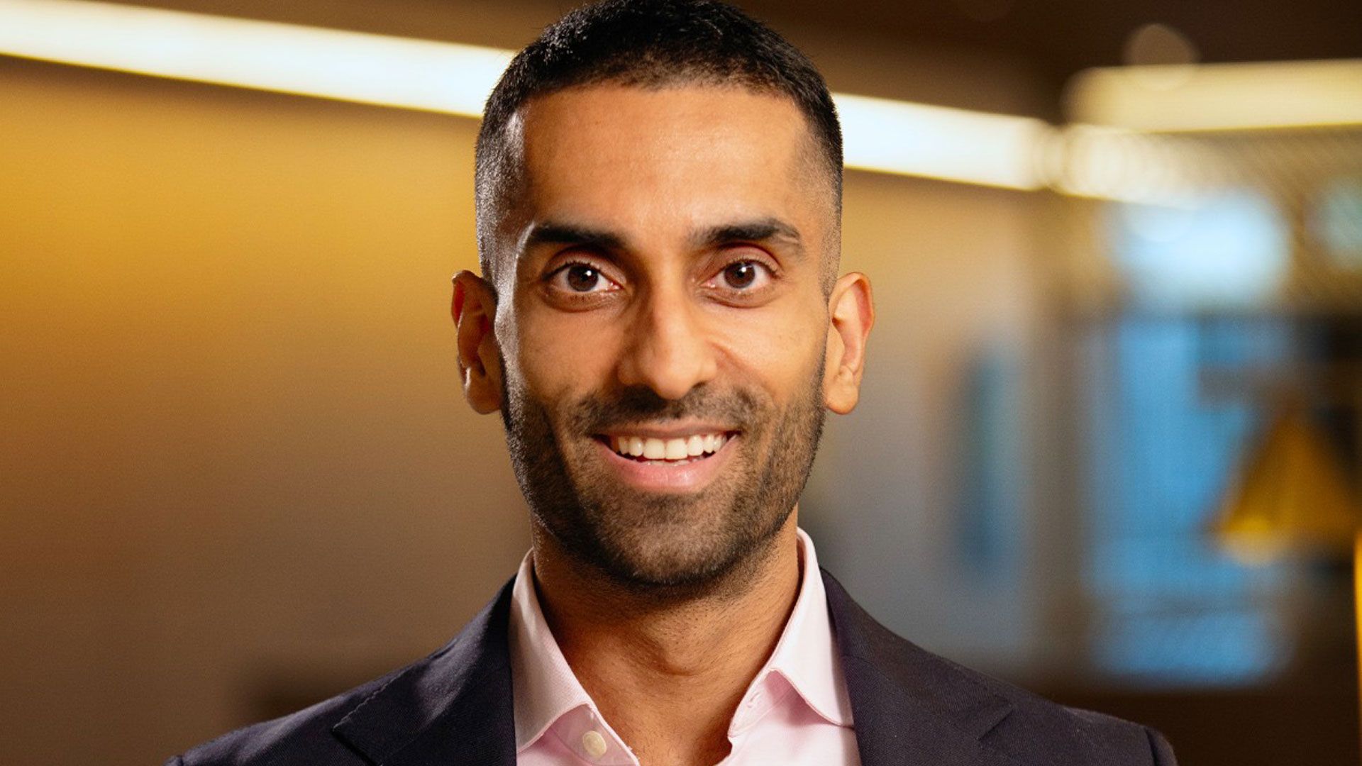 Prakash Kakkad, Unilever Chief Legal Officer and Group Company Secretary. Pakash is wearing a dark suit jacket and light pink shirt standing indoors in a warmly lit, modern office setting.