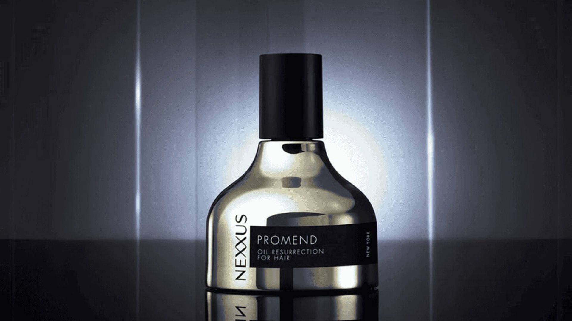 Nexxus Promend Oil Resurrection for Hair bottle with a sleek metallic finish and black cap, set against a dark reflective background with vertical light streaks and a soft glow.