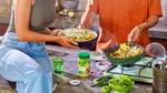 A man and a woman cooking and plating up a dish, with a Knorr Chicken Bouillon Powder jar on the counter.