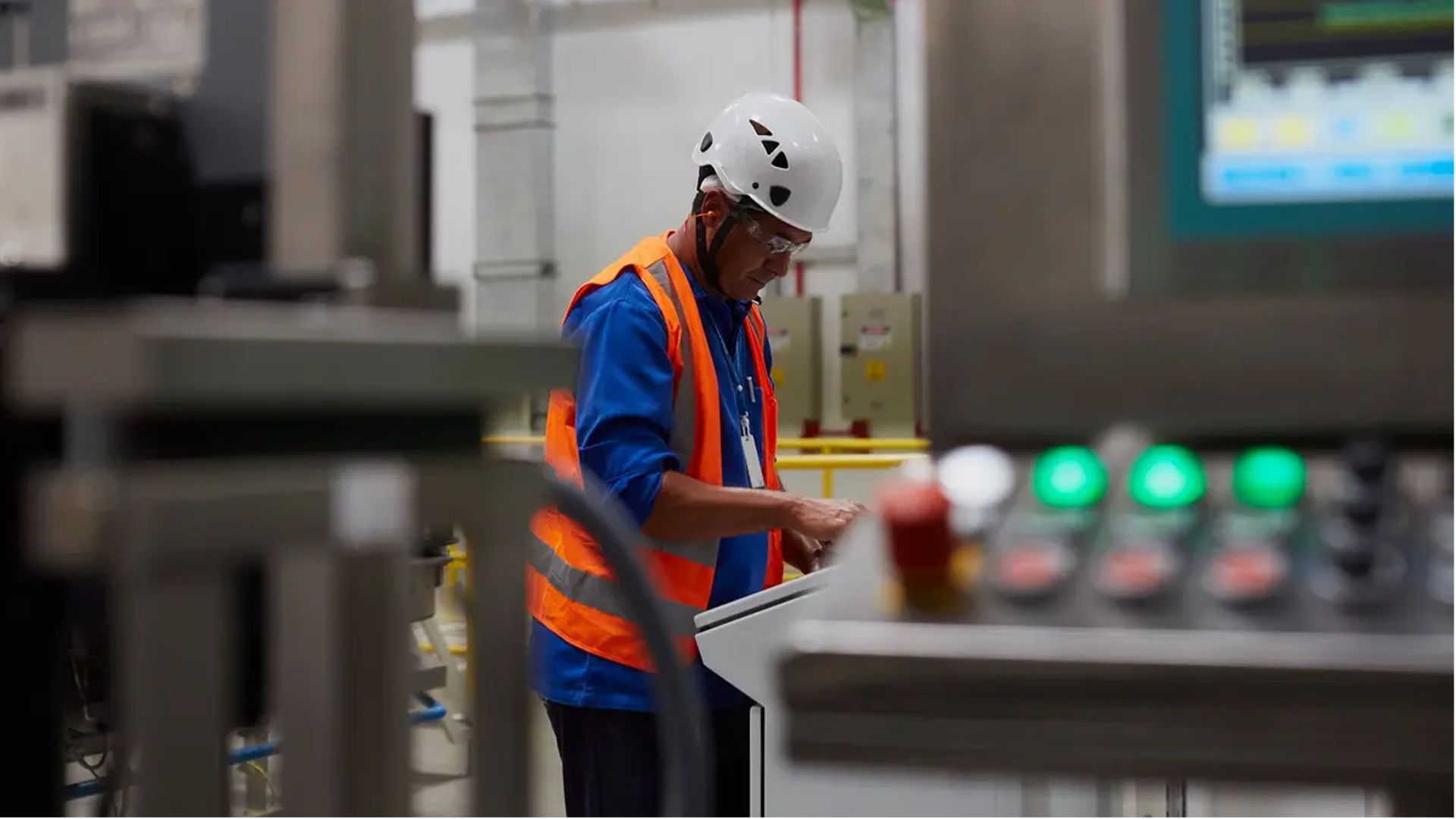 An employee in safety clothing operates a machine in a factory.