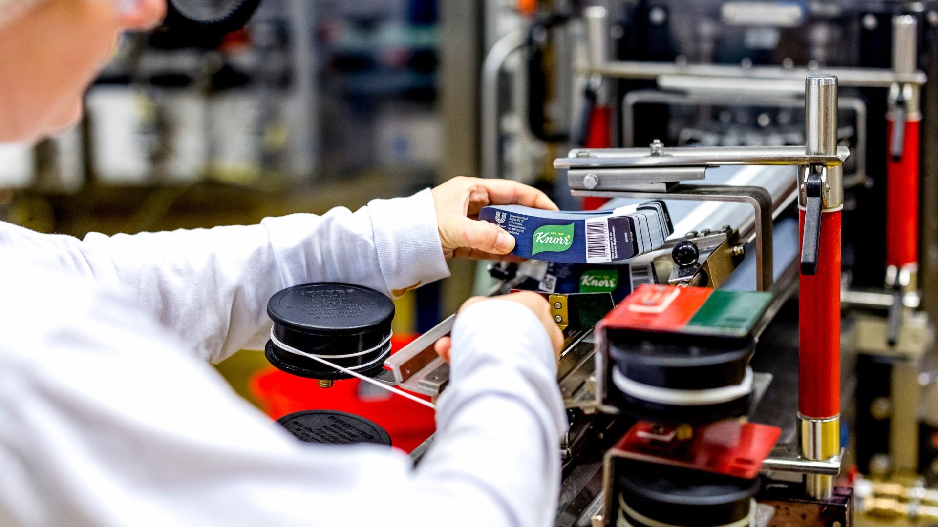 A close-up of a factory team member working on a Knorr production line