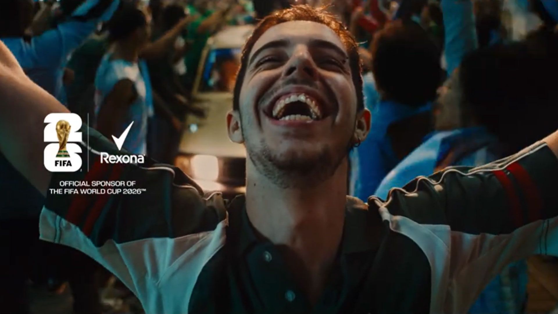 A person celebrating in a crowd infront of a car.