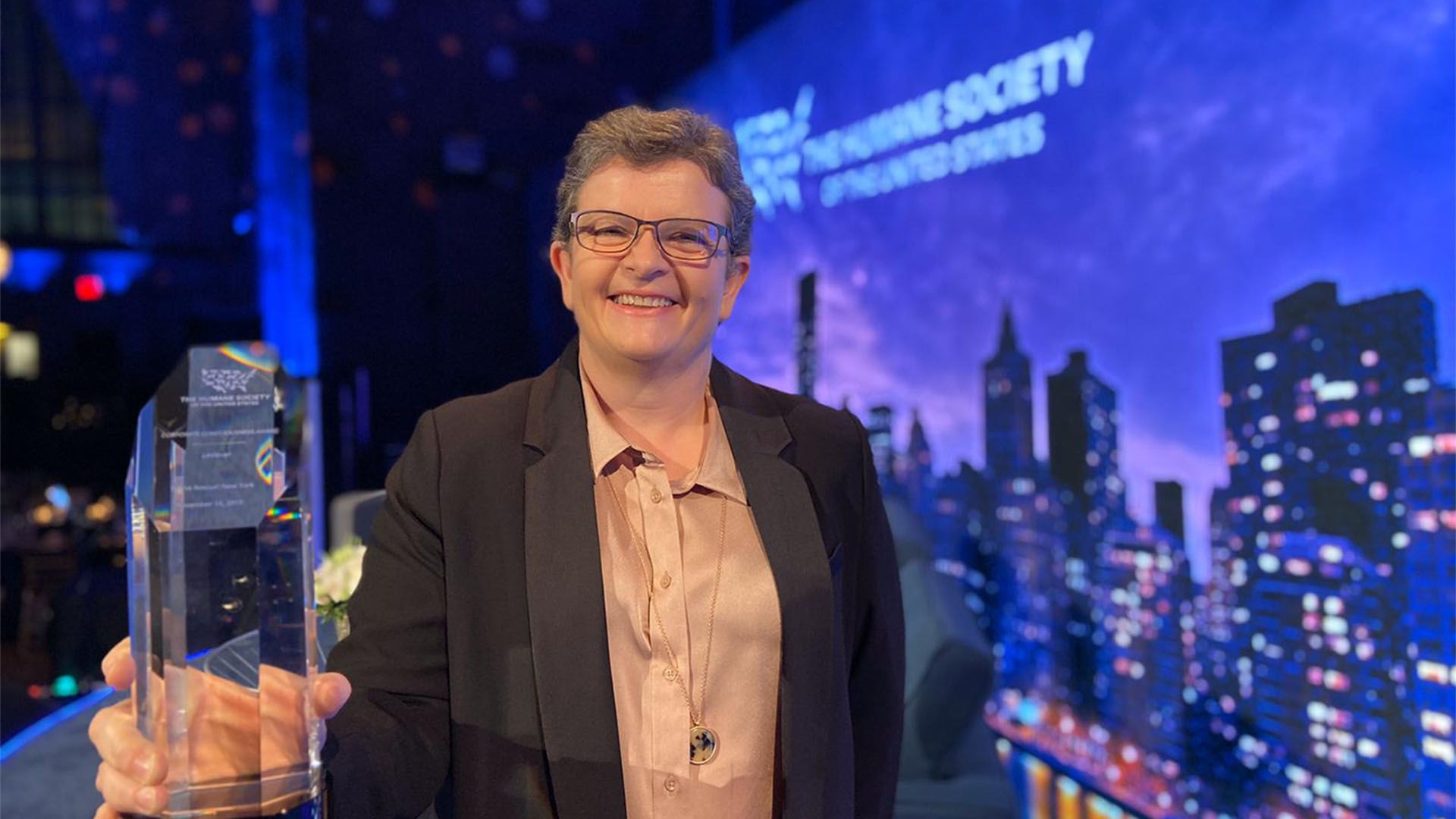 Julia smiling as she displays the Russell and Burch Award from the Humane Society of the United States