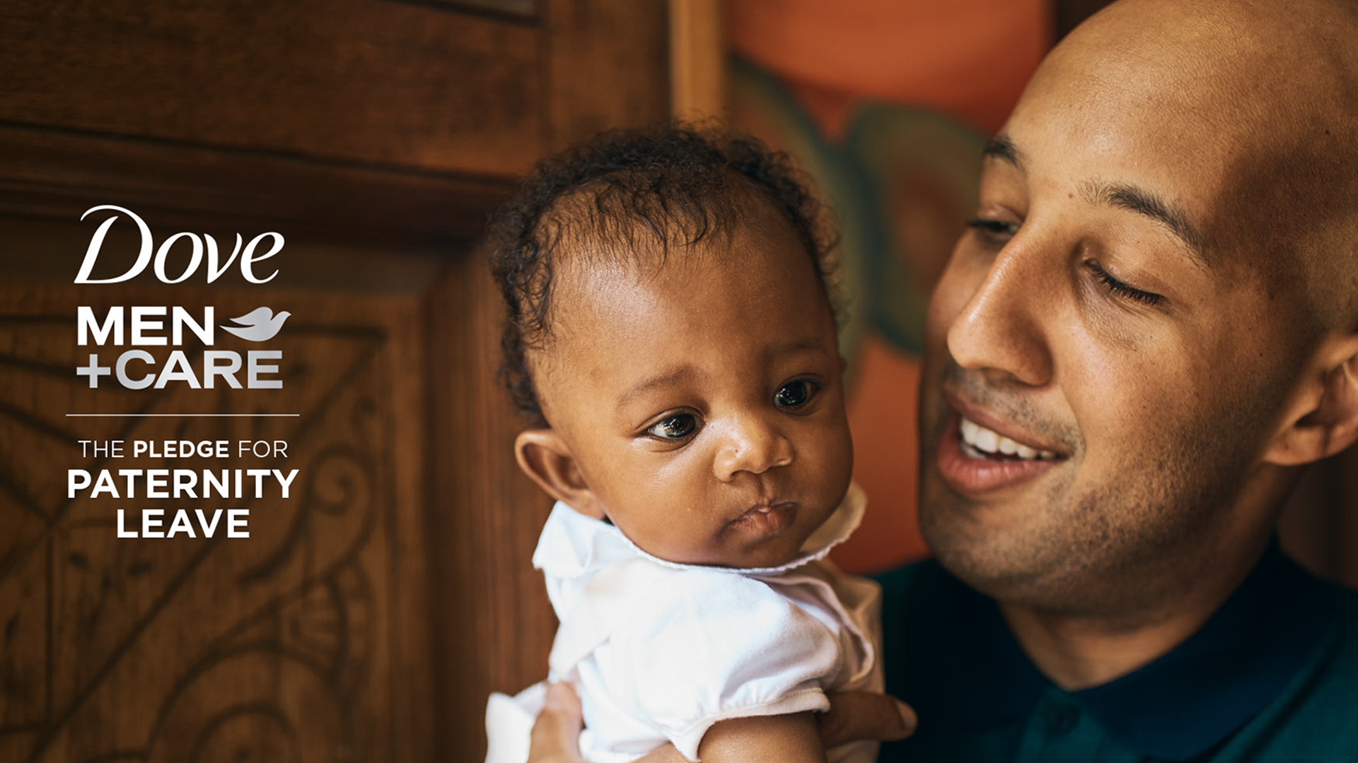 On the right is a dad holding a newborn baby and on the left is the Dove Men+Care logo. The text below it reads: ‘THE PLEDGE FOR PATERNITY LEAVE’.