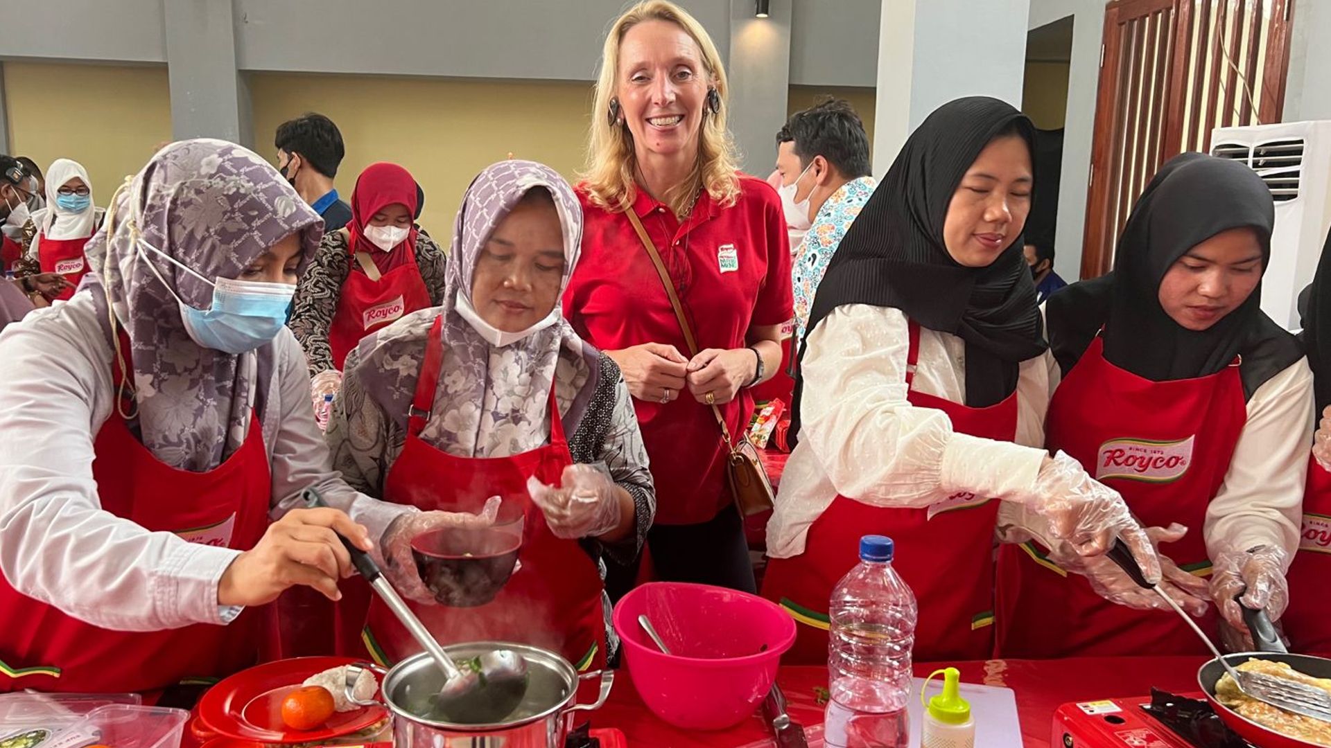 Hanneke standing behind women cooking  