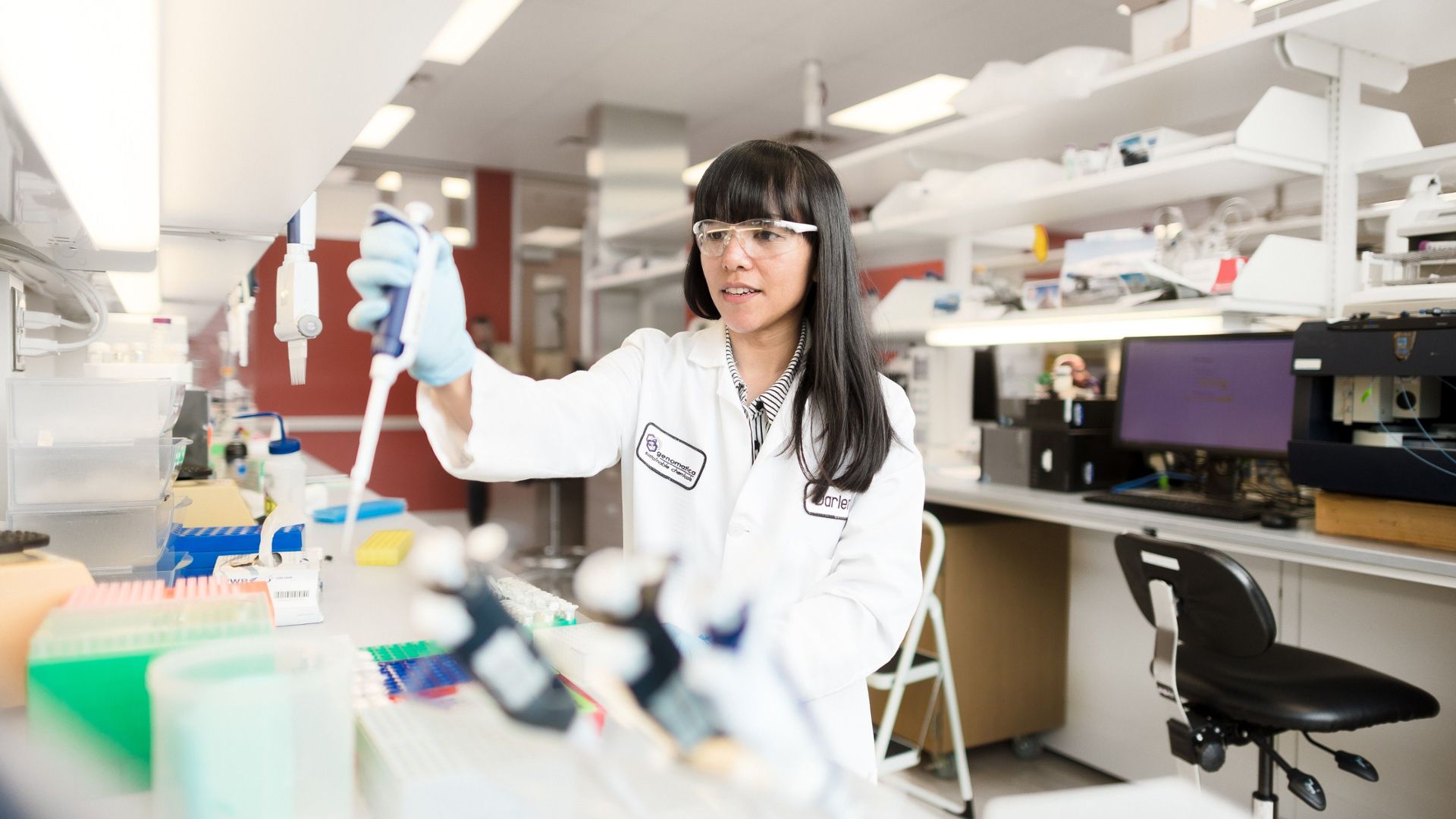 A woman in a white lab coat working at one of Geno’s biotech labs