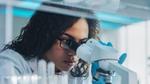 Woman looking through a microscope in a lab