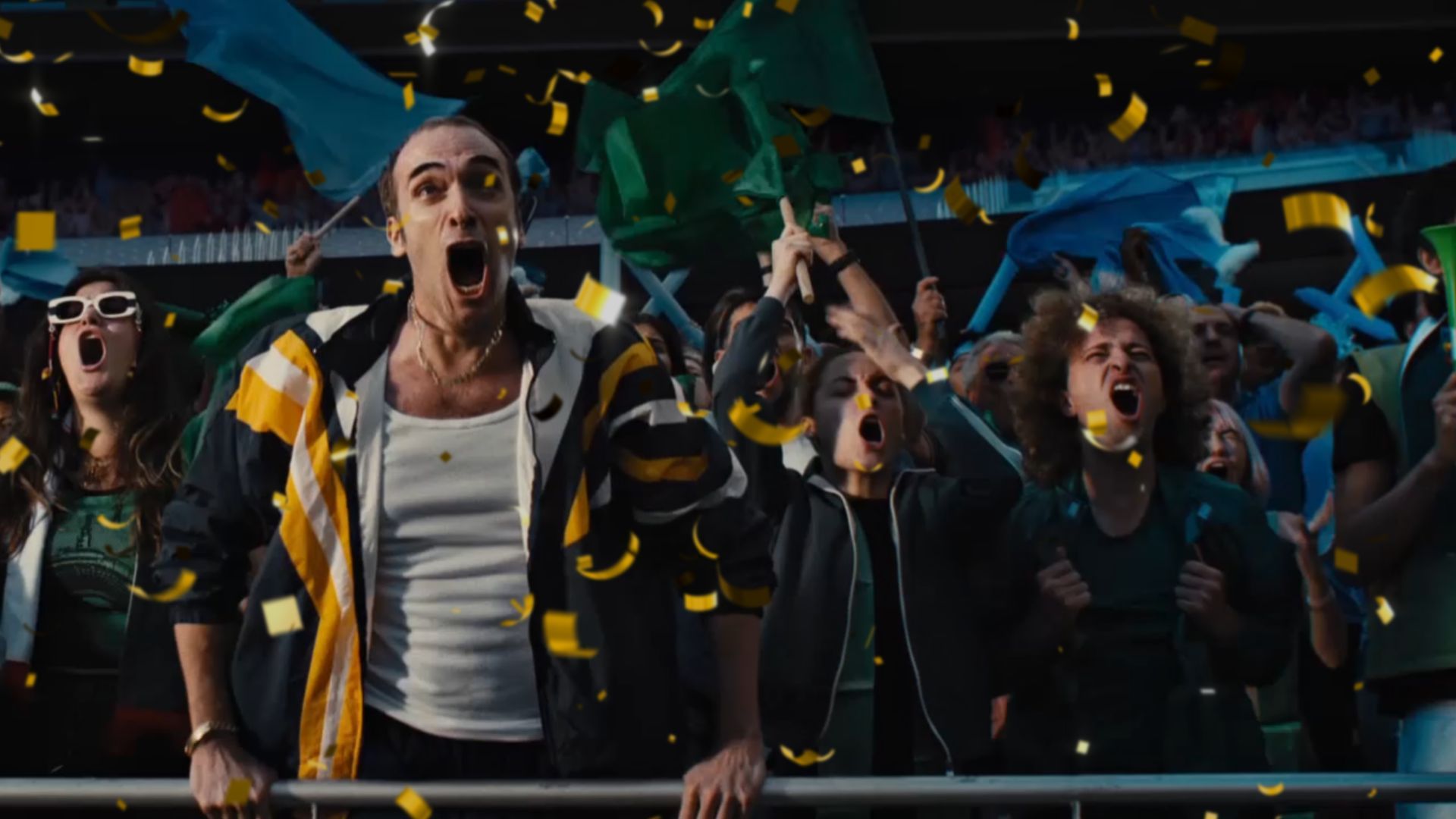 Excited football fans in a stadium cheer loudly as yellow confetti falls around them
