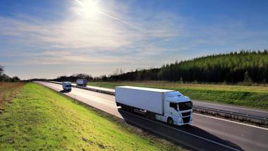 A white delivery truck driving on a motorway.
