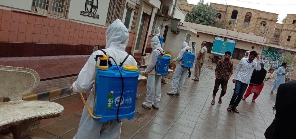 Men at work, with containers of Domex disinfectant strapped to their backs