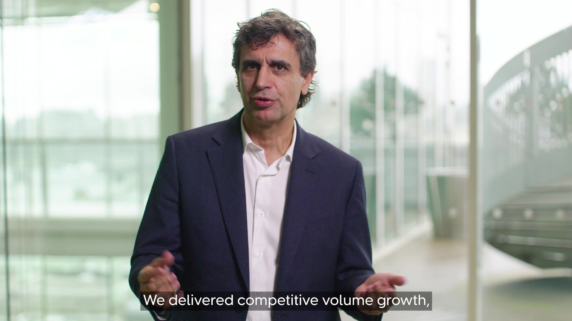 Fernando Fernandez, Unilever Chief Executive Officer, wearing a dark blazer and white shirt standing indoors in front of large windows. 