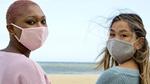 Two people wearing facemasks, one pink and one wearing grey.