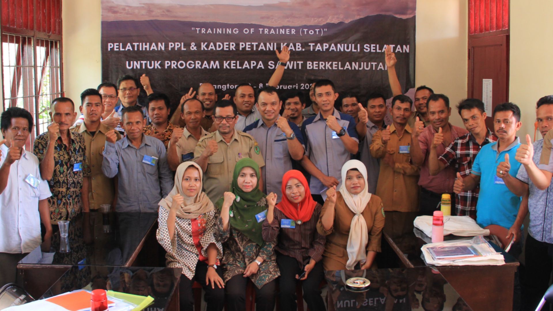 A large group of people in a training session with their thumbs up in approval